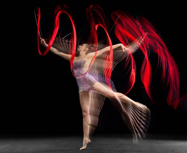 Ung vacker flicka rytmisk gymnast i rörelse isolerad i blandat ljus på mörk bakgrund. Stroboskop — Stockfoto