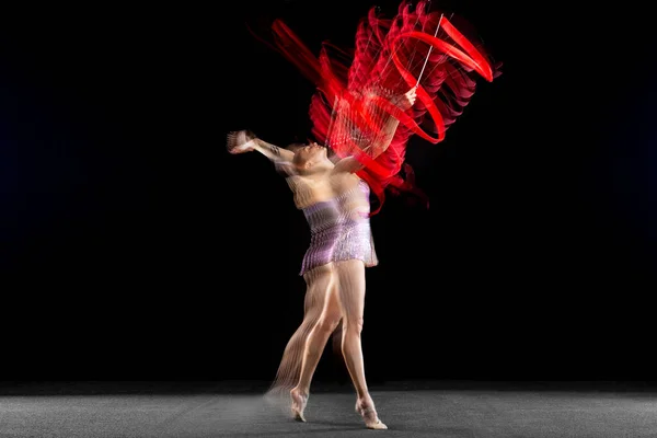 Hareket halindeki bir bayan ritmik jimnastikçi ve koyu arkaplanda karışık ışıkta izole edilmiş bir eylem. El ilanı — Stok fotoğraf