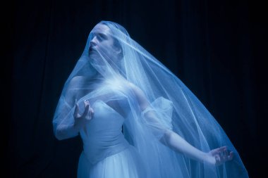 Genç, zarif balerina, sanat performansında hayalet gelin görüntüsü. Karanlık arka planda, neon ışıkta izole edilmiş..
