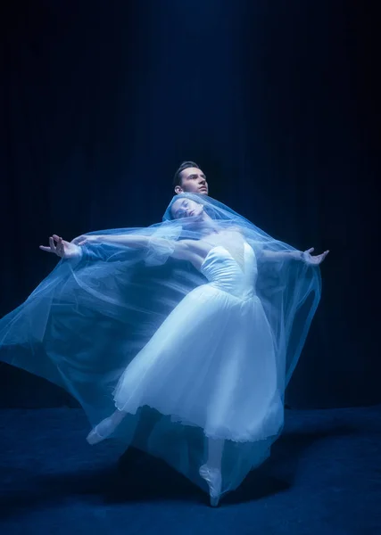 Молодая женщина в свадебном платье и мужчина, двое артистов балета в художественном перформансе танцуют изолированно на тёмном фоне. — стоковое фото