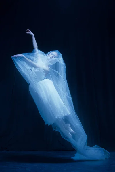 Jonge sierlijke balerina in beeld van spookbruid in kunstvoorstelling geïsoleerd op donkere achtergrond in neon licht. — Stockfoto