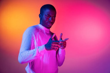 Genç, mutlu, Afrikalı yakışıklı bir adam. Gradyan pembe neon arka planda izole edilmiş..