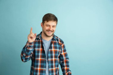 Açık mavi arka planda izole edilmiş günlük giysiler içinde beyaz sakallı genç bir adam..