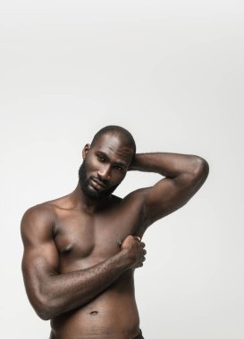 Genç yakışıklı kaslı Afrikalı adam beyaz arka planda yalnız poz veriyor. Güzellik kavramı, kozmetik, kaplıca.