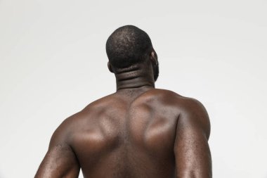 Beyaz arka planda yalnız poz veren yakışıklı, kaslı Afrikalı bir adamın portresi. Arka plan
