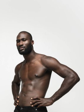 Genç yakışıklı kaslı Afrikalı adam beyaz arka planda yalnız poz veriyor. Güzellik kavramı, kozmetik, kaplıca.