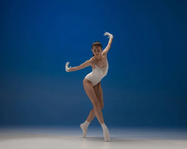 Giovane bella ballerina in azione isolata su sfondo blu. Concetto di bellezza, arte, spettacolo, teatro. — Foto Stock