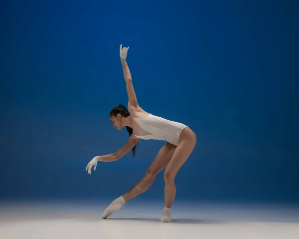 Jeune belle ballerine en action isolée sur fond bleu. Concept de beauté, art, spectacle, théâtre. — Photo