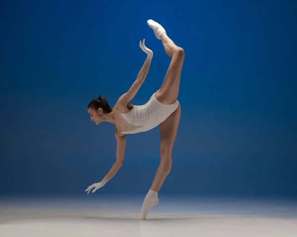 纤细娇嫩的年轻貌美的女孩，在蓝色背景下独自跳舞的女芭蕾舞演员. — 图库照片