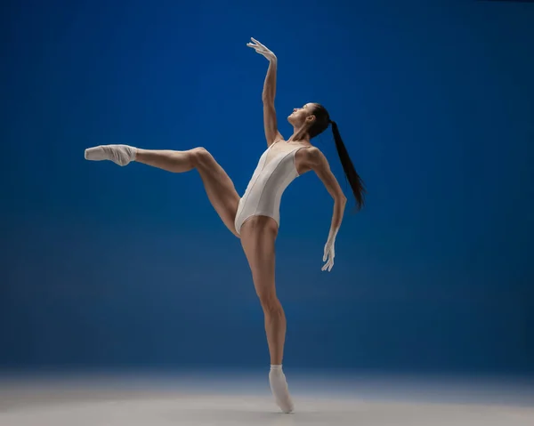 Gracieuse jeune belle fille, danseuse de ballet féminin dansant isolé sur fond bleu. — Photo