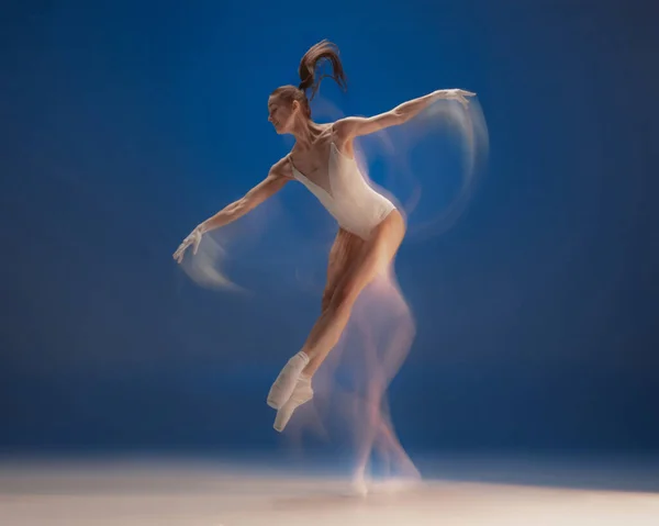 Genadig jong mooi meisje, vrouwelijke balletdanseres dansend geïsoleerd over blauwe achtergrond. Reflectie-effect — Stockfoto