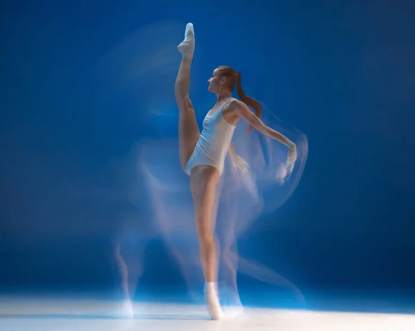 Belle jeune fille gracieuse, danseuse de ballet féminine dansant isolée sur fond bleu. Effet de réflexion — Photo