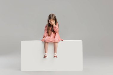 Gri stüdyo arka planında izole edilmiş küçük beyaz kız portresi..