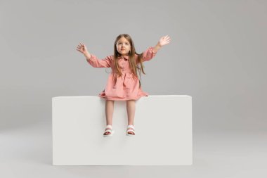 Gri stüdyo arka planında izole edilmiş küçük beyaz kız portresi..