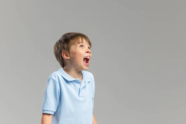 Halblanges Porträt eines kaukasischen Jungen, der isoliert vor grauem Studiohintergrund posiert. — Stockfoto