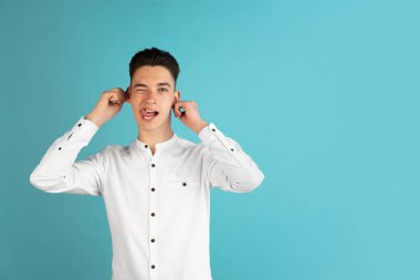 Beyaz gömlekli beyaz çocuk mavi stüdyo arka planında izole edilmiş. Yüz ifadeleri, insan duyguları kavramı.