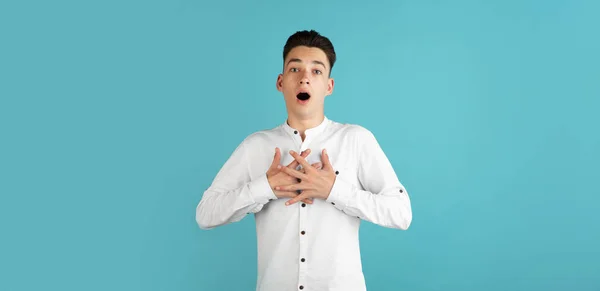 Jovem caucasiano de camisa branca isolado no fundo do estúdio azul. Conceito de expressões faciais, emoções humanas. — Fotografia de Stock