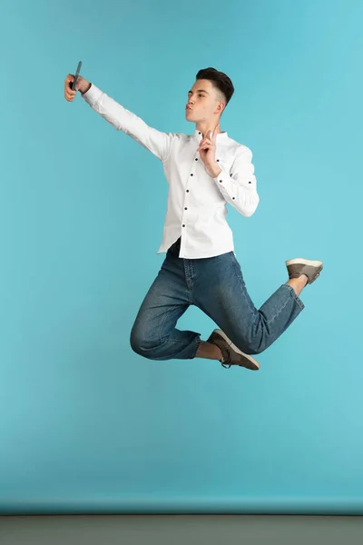 Jong gelukkig blank jongen, tiener in casual kleding springen geïsoleerd op licht blauw achtergrond. — Stockfoto