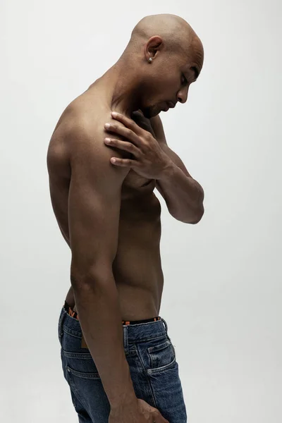 侧视图。一个年轻的、肌肉发达的非洲男子摆出孤立的架势，没有白人背景。美容、化妆品、温泉的概念. — 图库照片