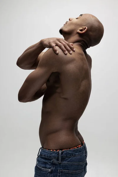 Seitenansicht. Ein junger muskulöser afrikanischer Mann posiert isoliert vor weißem Hintergrund. Konzept der Schönheit, Kosmetik, Wellness. — Stockfoto