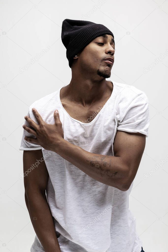 Portrait of young muscled African man, fashion model isolated over white background.