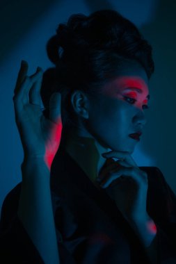 Genç ve güzel bir Japon 'un portresi. Ulusal giyimli bir kadın. Koyu mavi arka planda soyutlanmış bir şekilde poz veriyor..