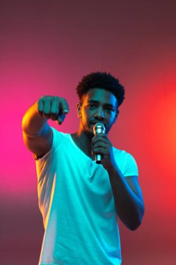 Afrikalı yakışıklı genç adam stüdyoda mikrofona şarkı söylüyor. Müzik konsepti.