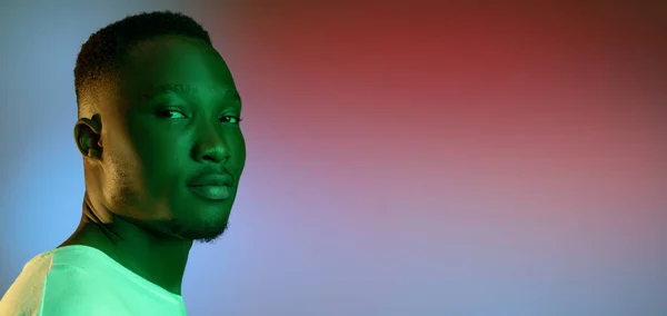 Afrikalı genç bir adamın parlak stüdyo arkaplanındaki neon ışıklı portresini yakından çek. Sıradan tarzda yakışıklı bir erkek model.. — Stok fotoğraf