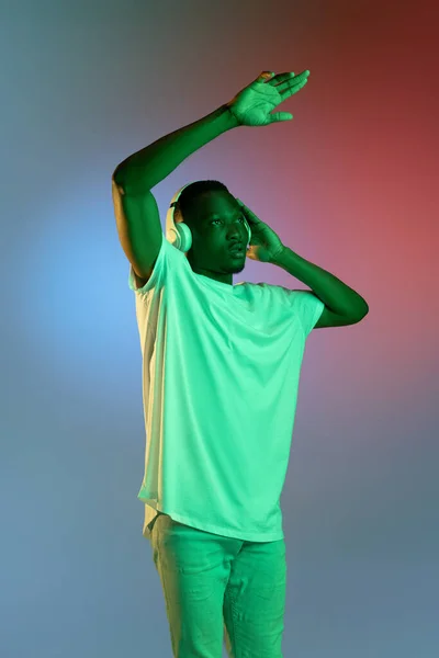 Retrato de jovem africano sobre fundo brilhante estúdio em luz de néon. Conceito de emoções, expressão facial, juventude. — Fotografia de Stock