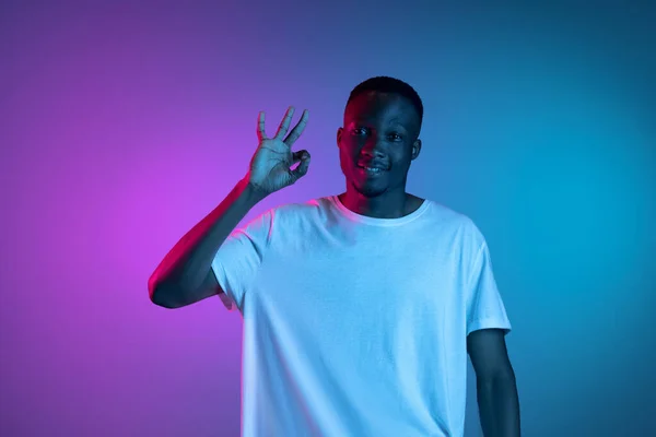 Young happy smiling african man posing in neon light on gradient background. Concept of emotions, facial expression. — Stock Photo, Image