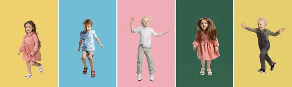 Collage of three little kids, boys and girl jumping isolated on multicolored studio background. — Stock Photo, Image