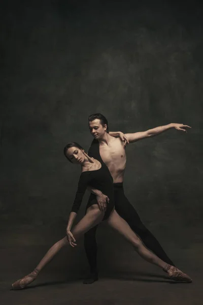 Красивые грациозные женщина и мужчина, артисты балета в художественном перформансе танцуют изолированно на темном фоне — стоковое фото