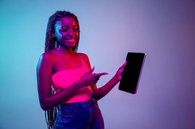 Afro saç stili olan genç Afrikalı kadın leylak rengi neon arka planda izole edilmiş. Stüdyo çekimi. Yüz ifadesi ve insan duyguları kavramı