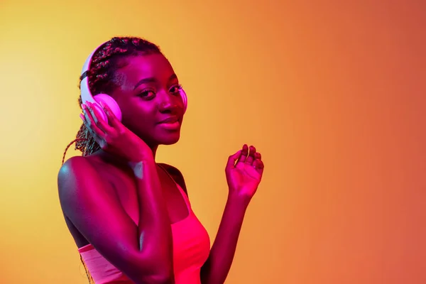 Glad ung vacker afrikansk flicka, kvinnlig modell isolerad på gul bakgrund i neon ljus. — Stockfoto