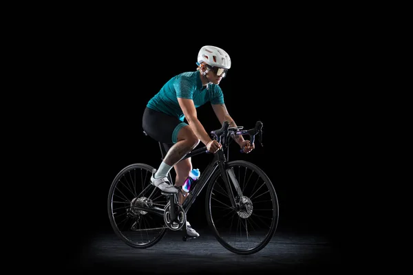Professionelle junge Radfahrerin auf Rennrad isoliert über schwarzem Studiohintergrund. — Stockfoto