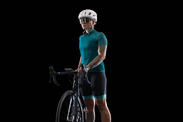 Profesional joven ciclista femenina en bicicleta de carretera aislado sobre fondo de estudio negro. — Foto de Stock