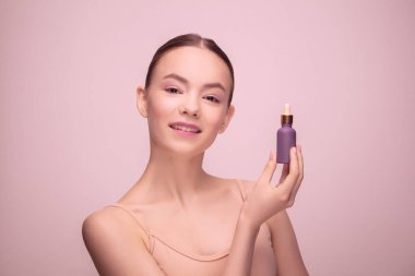 Açık pembe stüdyo arka planında izole edilmiş güzel bir genç kadının portresi. Kadın güzelliği kavramı, yüz bakımı, hassasiyet, duygusallık.