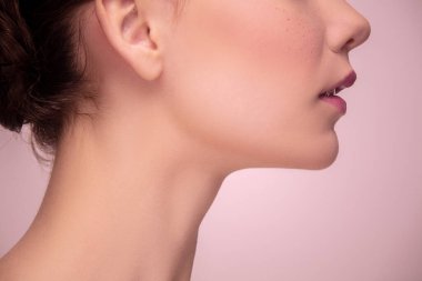 Açık pembe stüdyo arka planında izole edilmiş güzel bir genç kadının portresi. Kadın güzelliği, stili, makyaj anlayışı