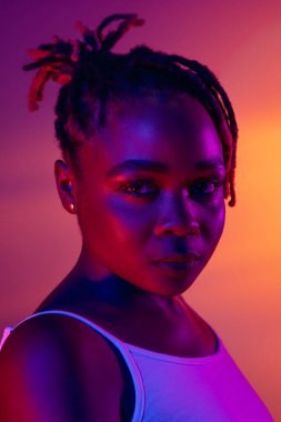 Gülümseyen genç Afrikalı güzel kız parlak stüdyo arkaplanından izole edilmiş neon ışıkta. Yan görünüm