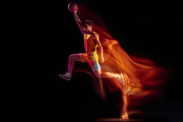 Joven jugador de baloncesto caucásico entrenando aislado sobre fondo negro en luces mixtas de neón. —  Fotos de Stock