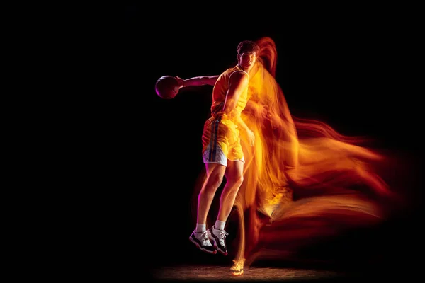 在混合霓虹灯下，年轻的白人篮球运动员在黑色背景下进行训练. — 图库照片