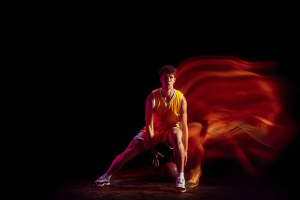 年轻的白种人职业篮球运动员在混合霓虹灯下，在黑色背景下进行隔离运动. — 图库照片