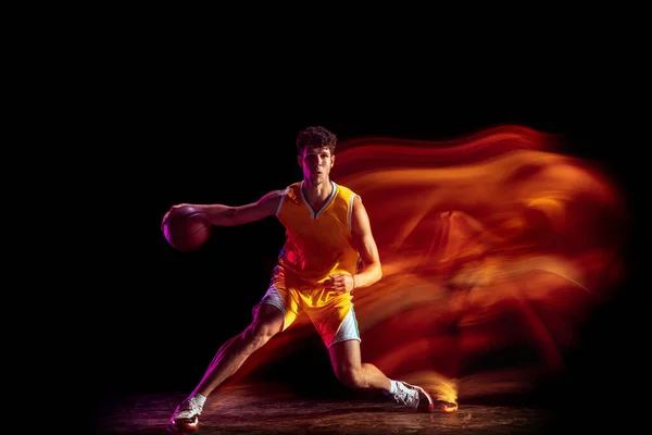 Ung kaukasisk professionell basketspelare tränar isolerad på svart bakgrund i blandade neonljus. — Stockfoto