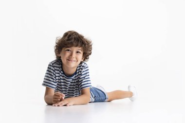 Beyaz stüdyo arka planında izole edilmiş küçük anaokulu çocuğunun portresi.