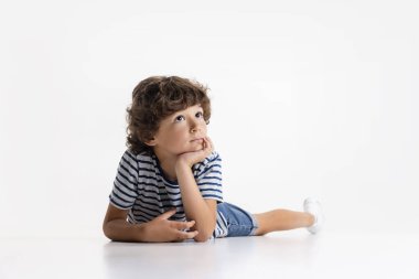 Beyaz stüdyo arka planında izole edilmiş küçük anaokulu çocuğunun portresi.