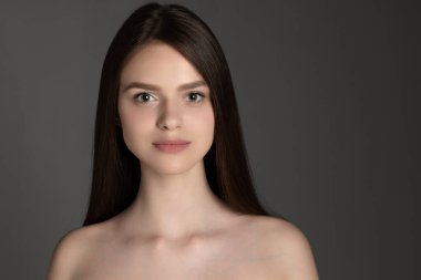 Gri stüdyo arka planında izole edilmiş güzel beyaz bir kızın stüdyo görüntüsü..