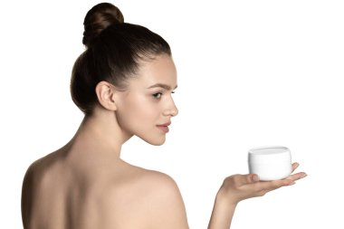 Beyaz stüdyo arka planında izole edilmiş bir kavanoz yüz kremi tutan güzel beyaz bir kız..