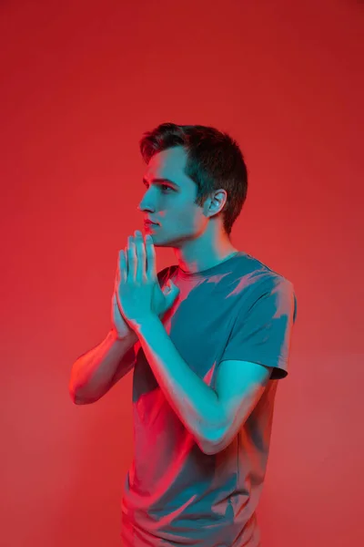 赤いネオンの背景に孤立した若い白人男性の垂直肖像画。人間の感情や表情の概念. — ストック写真