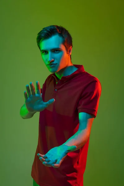 Un joven hombre caucásico con ropa casual aislado sobre fondo de neón verde. Concepto de emociones humanas, expresión facial. — Foto de Stock