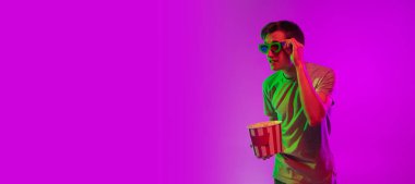 Sinema izliyordum. 3 boyutlu gözlüklü patlamış mısırlı beyaz bir adam pembe stüdyo arka planında neon ışıkta izole edilmiş..